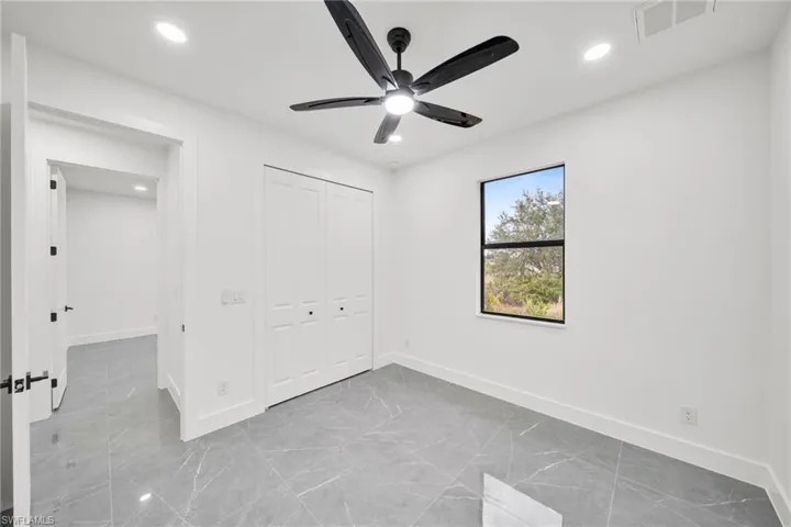 Unfurnished bedroom featuring recessed lighting, a closet, a ceiling fan, and light marble finish floors