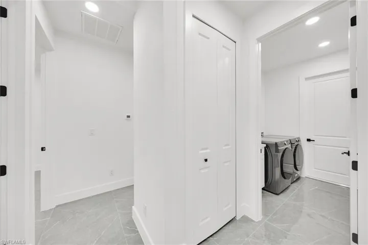 Washroom featuring recessed lighting, independent washer and dryer, and light marble finish flooring