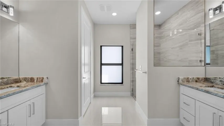 Bathroom with two vanities, a shower stall, and recessed lighting