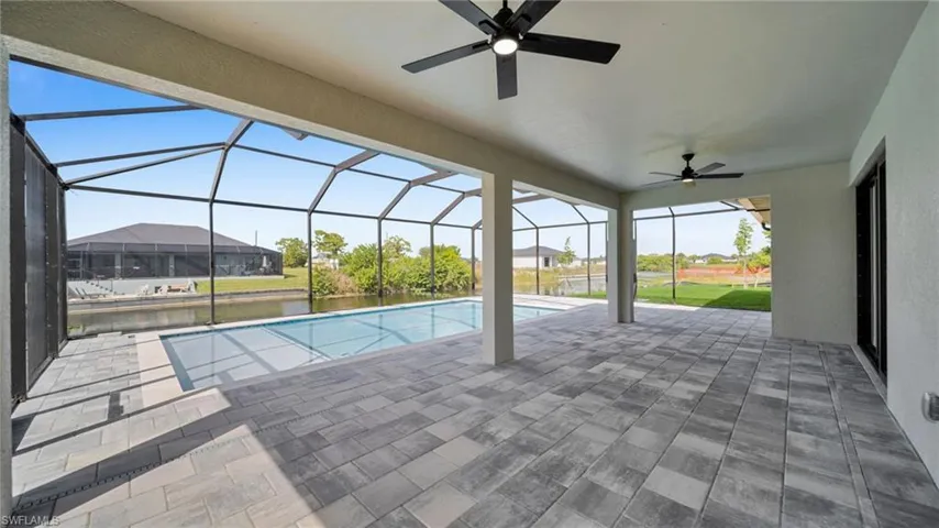Swimming pool featuring glass enclosure, a ceiling fan, a sunroom, a patio area, and a water view