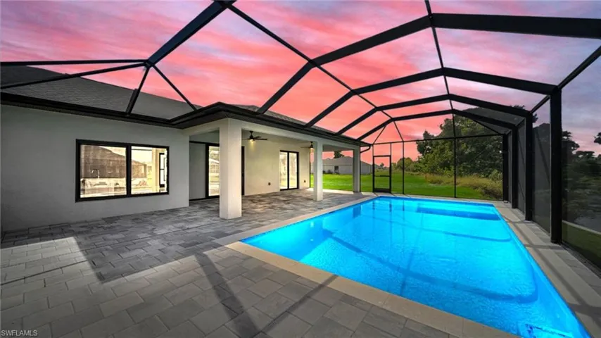 Pool at dusk featuring ceiling fan, a sunroom, glass enclosure, and an outdoor pool