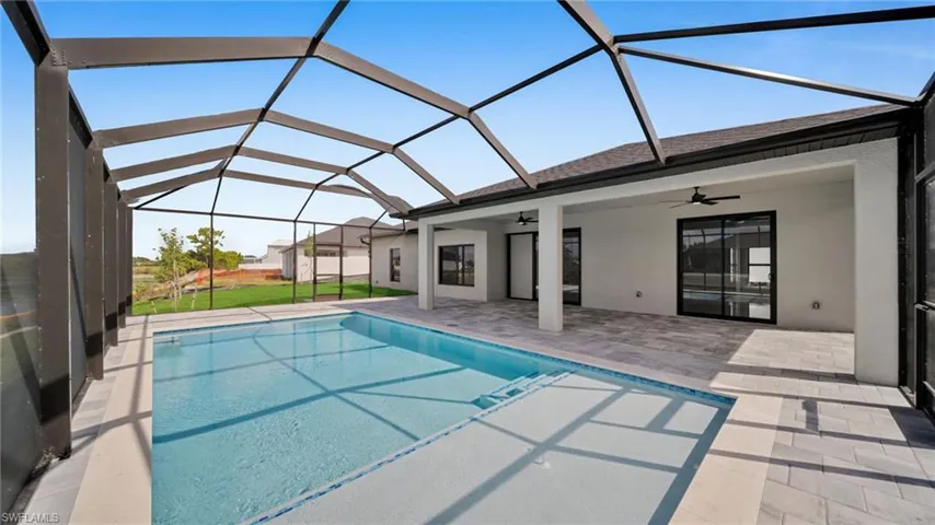 Outdoor pool with a sunroom, a ceiling fan, a patio area, glass enclosure, and a yard