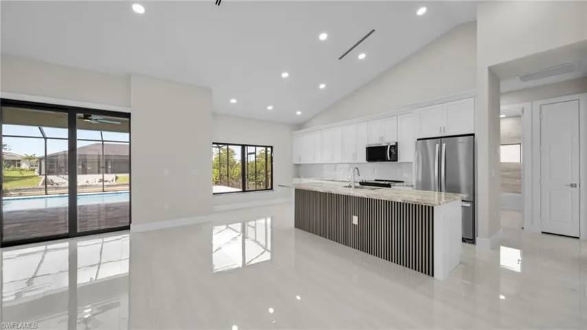 Kitchen with stainless steel appliances, a center island with sink, recessed lighting, white cabinets, and tasteful backsplash