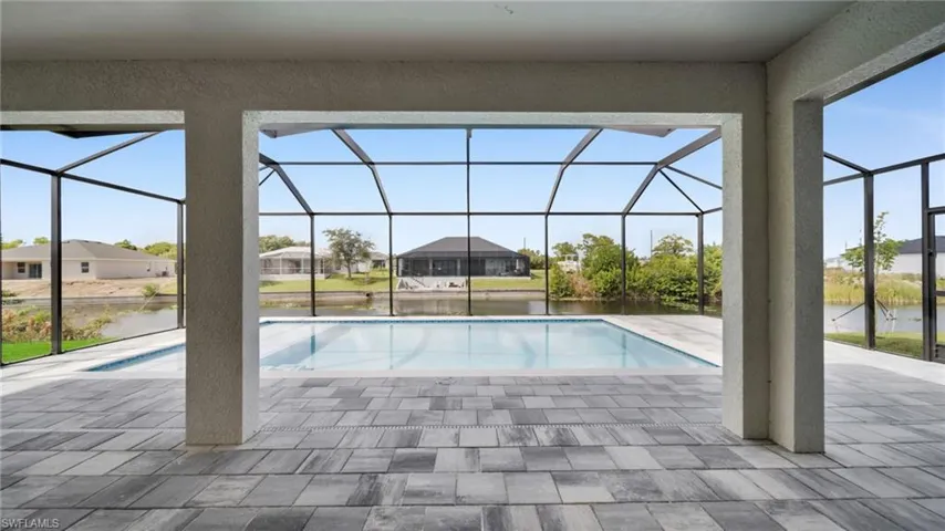 Outdoor pool featuring a sunroom, a water view, a lanai, and a patio area