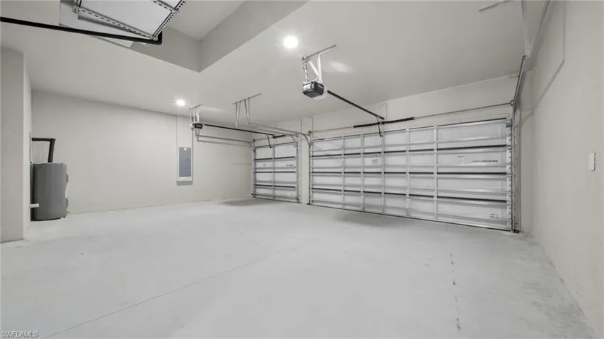 Garage featuring water heater, electric panel, and a garage door opener