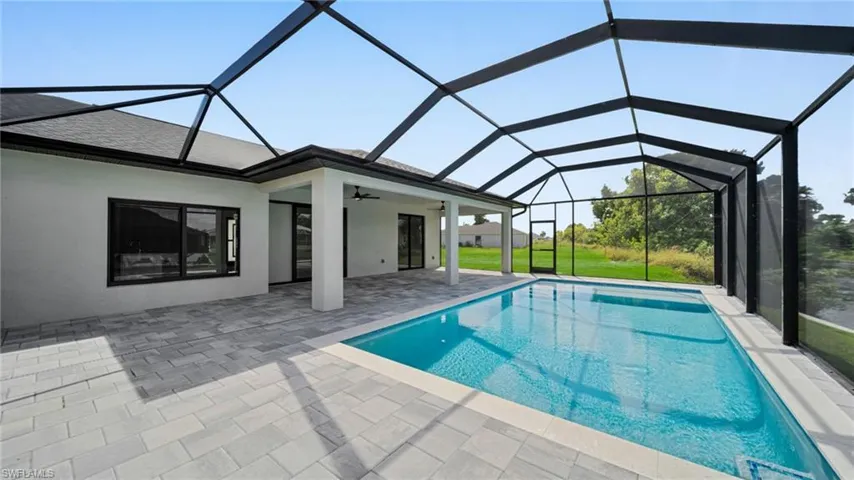 Swimming pool featuring ceiling fan, a sunroom, a lanai, a patio area, and a yard
