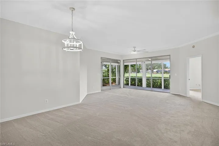 Unfurnished living room featuring ornamental molding, light carpet, a ceiling fan, and a chandelier