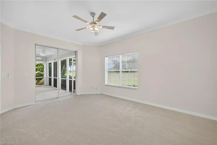 Carpeted empty room featuring ornamental molding and ceiling fan