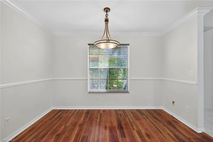 Unfurnished dining area featuring dark wood finished floors and ornamental molding