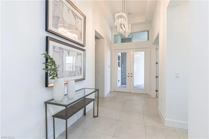 Tiled entrance foyer featuring a chandelier and french doors