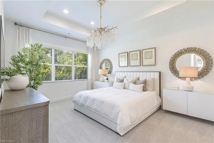 Carpeted bedroom with a chandelier and a tray ceiling