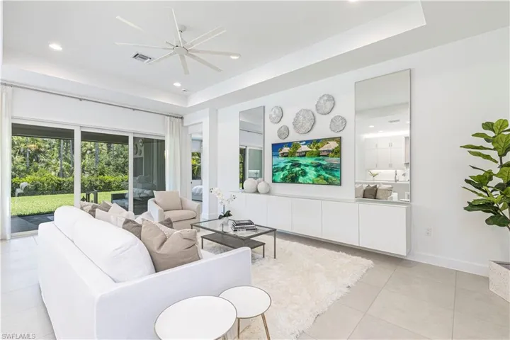 Tiled living room with ceiling fan and a tray ceiling