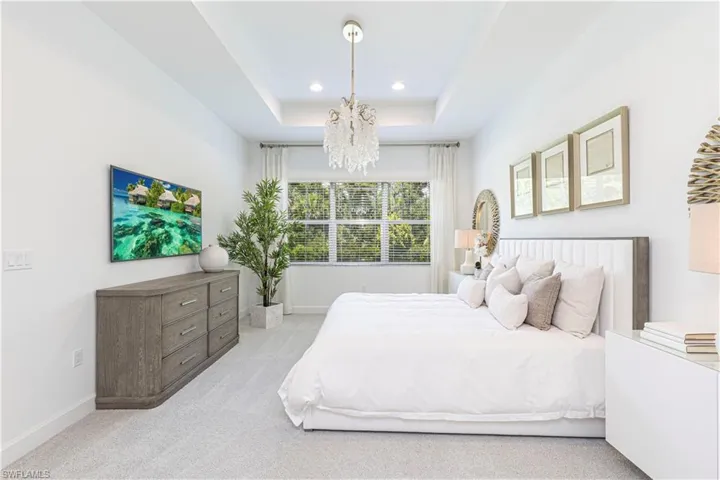Carpeted bedroom with a tray ceiling and an inviting chandelier