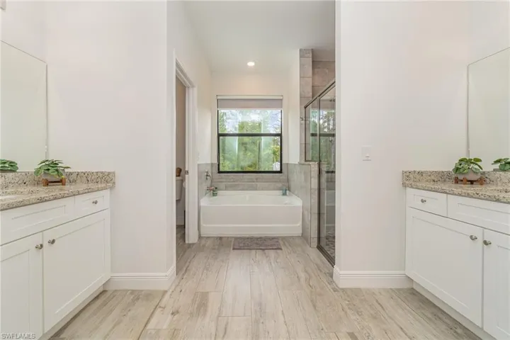 Bathroom featuring a shower stall, vanity, a garden tub, light wood-style flooring, and recessed lighting