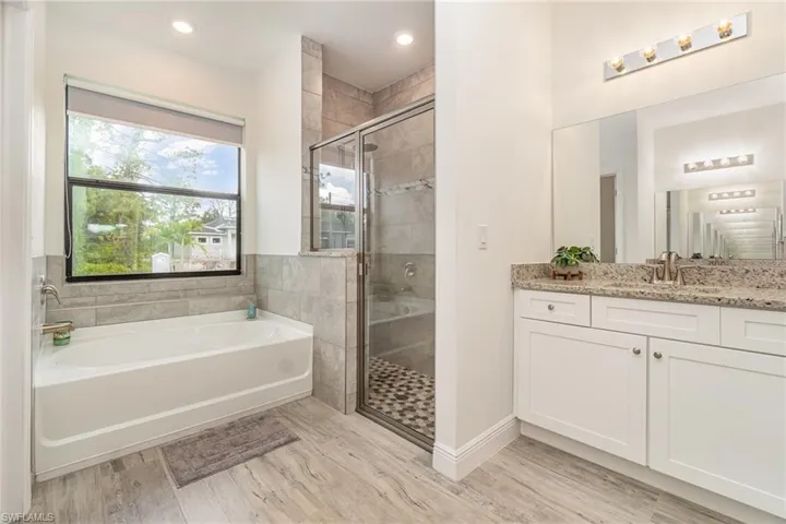 Bathroom featuring vanity, a garden tub, a shower stall, light wood finished floors, and recessed lighting