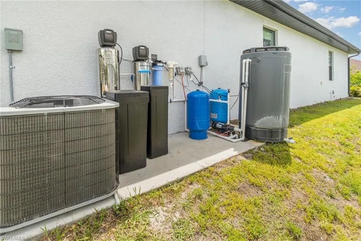 Exterior view of stucco siding, a water softener, and a water pressure tank