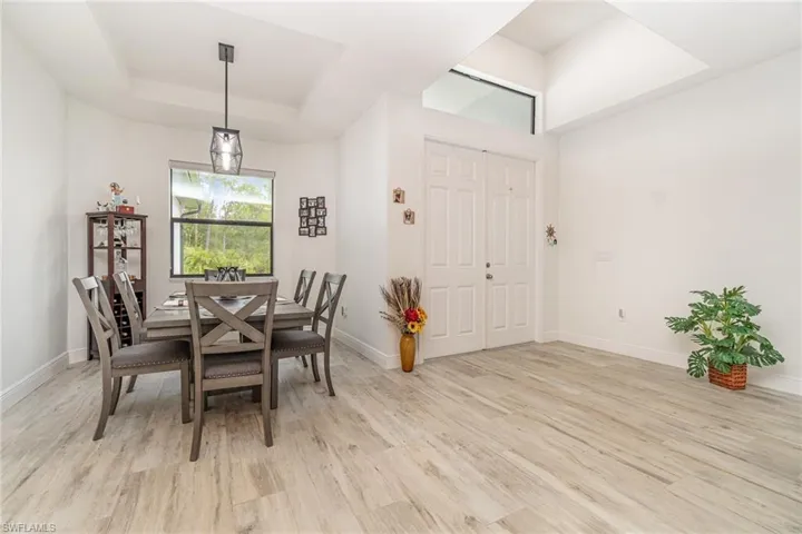 Dining space with a raised ceiling and light wood-type flooring