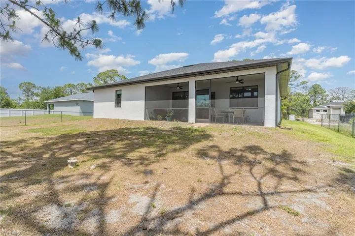 Rear view of house featuring a fenced backyard, a ceiling fan, stucco siding, and a sunroom
