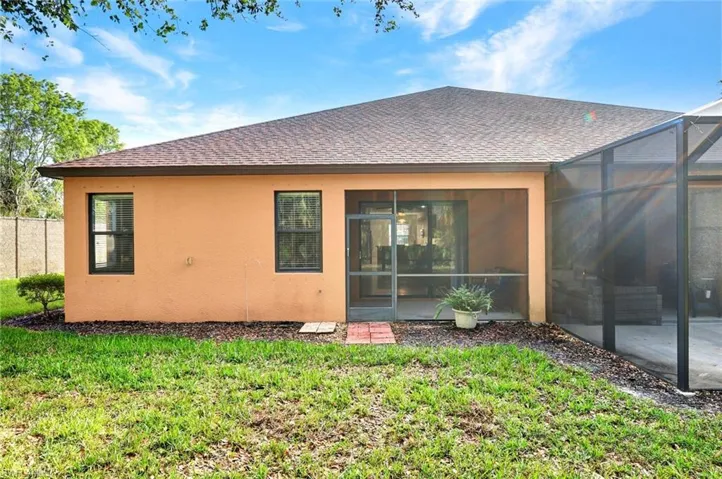 Rear view of property with a lawn, a lanai
