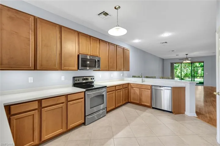 Kitchen featuring kitchen peninsula, appliances with stainless steel finishes, ceiling fan, sink, and hanging light fixtures