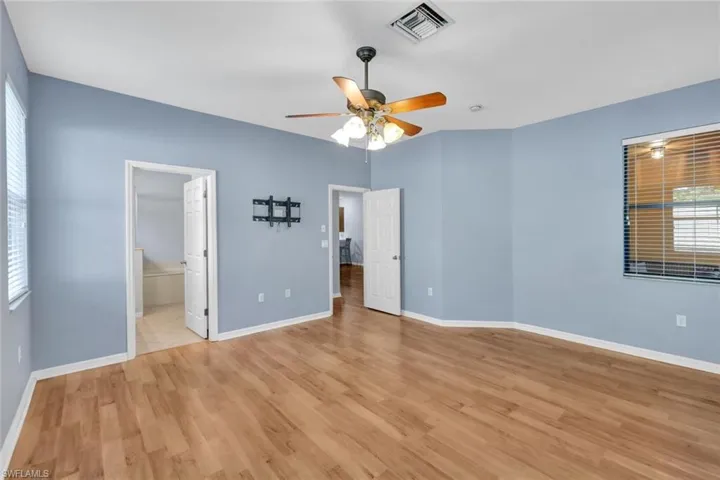 Main bedroom featuring light wood-type flooring, ensuite bath, and ceiling fan