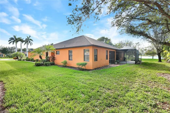 View of property exterior with a yard and screen lanai