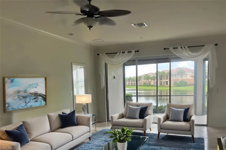 Living room featuring a wealth of natural light, a water view, and ornamental molding