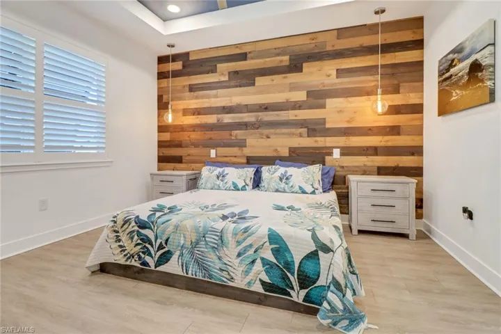 Bedroom with light wood-type flooring and wooden walls