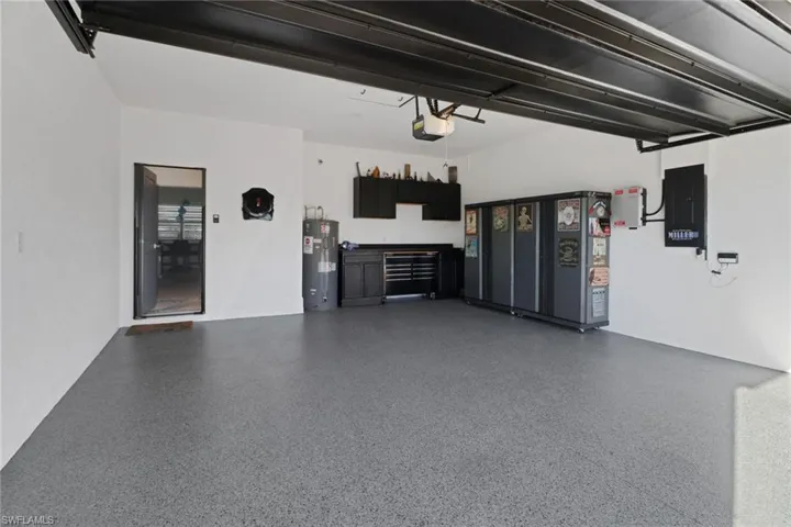Garage featuring a garage door opener, electric water heater, and electric panel