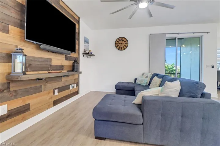 Living room featuring hardwood / wood-style flooring, ceiling fan, and wood walls