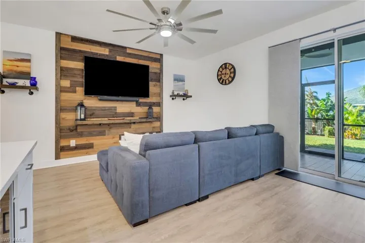 Living room featuring light hardwood / wood-style flooring, ceiling fan, and wood walls