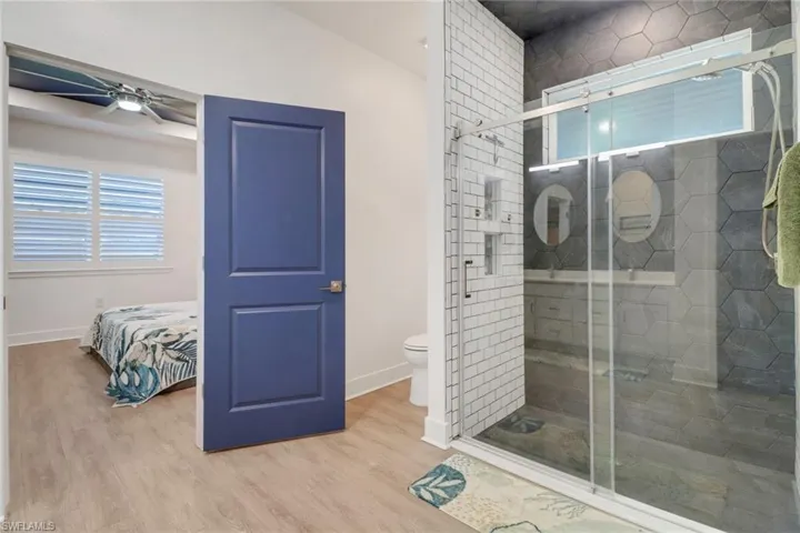 Bathroom with ceiling fan, wood-type flooring, vaulted ceiling, toilet, and a shower with shower door