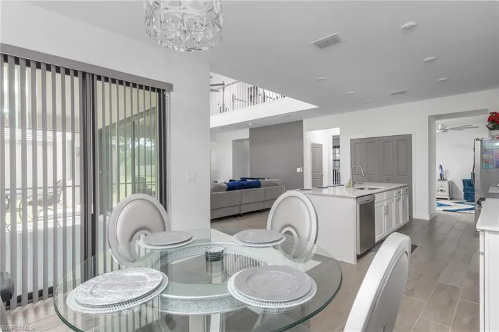 Dining area featuring a glass-top table, overhead contemporary light fixture, and vertical blinds on sliding glass doors