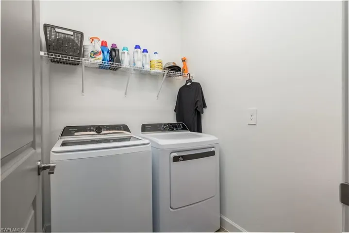 Dedicated laundry area featuring a washer and dryer, an overhead wire shelving unit, and light gray wall paint