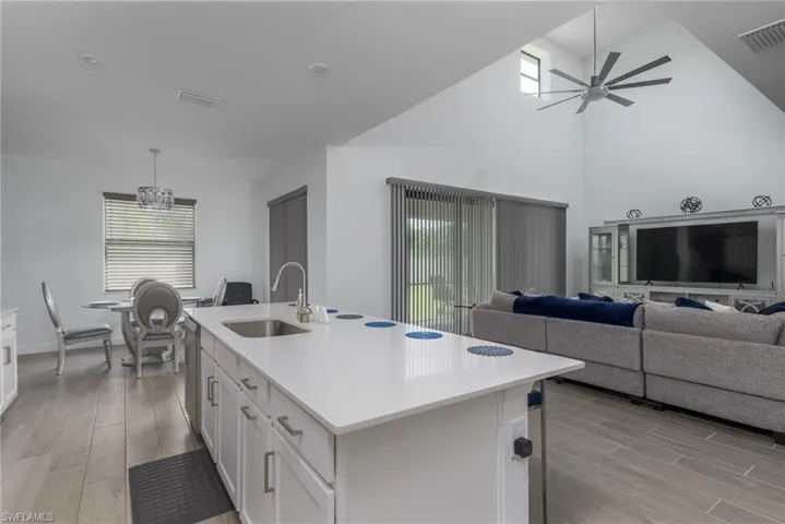 Open-concept interior featuring a spacious kitchen island with a single-basin sink, quartz-finish countertop, and white cabinetry