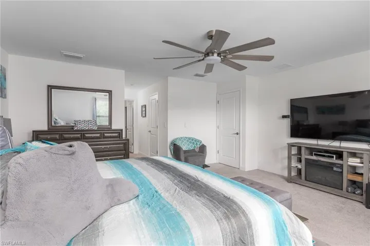 Spacious room featuring neutral carpeting, white walls, and a modern ceiling fan with lighting