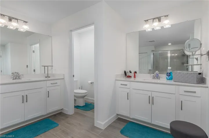 Dual vanities featuring white shaker cabinetry, light countertops, and brushed nickel hardware