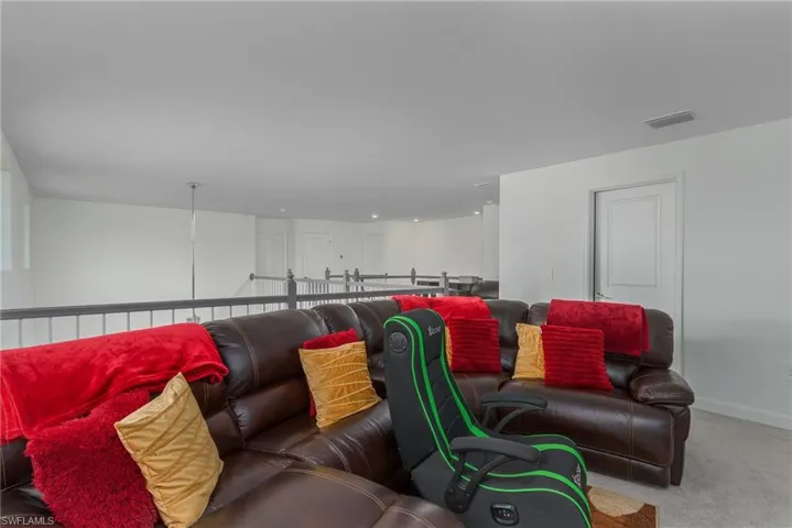 Upper-level landing featuring light gray carpeting, white painted walls, and a dark railing with white balusters