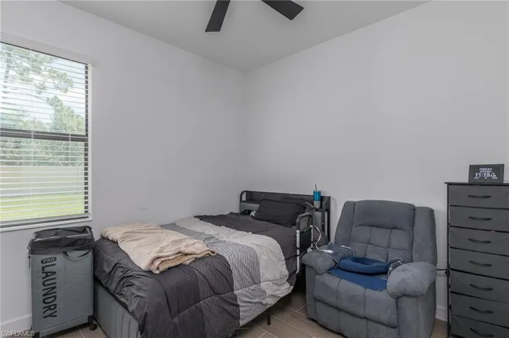 Bright room featuring a window with horizontal blinds, a ceiling fan, light-toned walls, and wood-finish flooring
