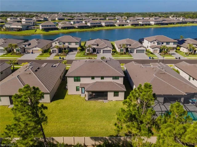 Aerial perspective featuring a manicured lawn, established pine trees, and a beige privacy fence