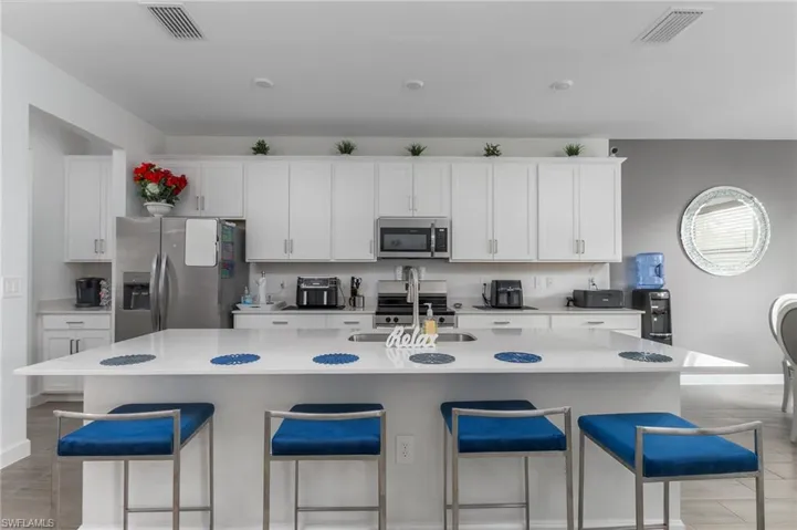 Modern kitchen featuring white cabinetry, a large center island with seating, stainless steel appliances, and recessed lighting