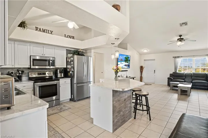 A large central island offers additional prep space and doubles as a casual dining area, perfect for gatherings.