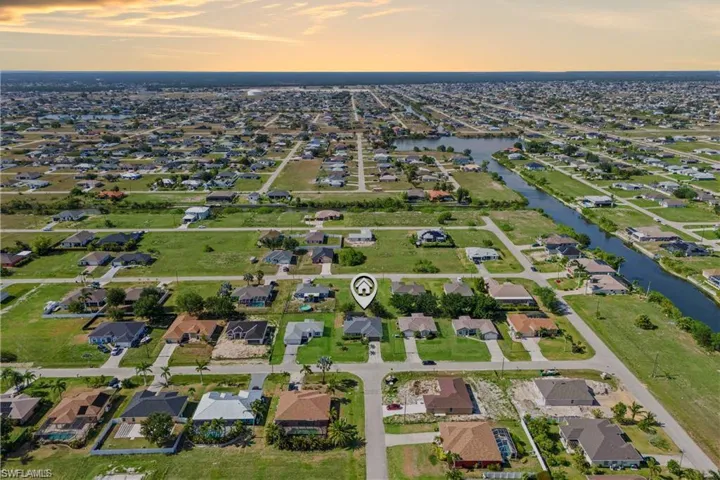 The aerial view showcases the home in a peaceful, well-landscaped community, with spacious properties. In the distance, a serene water view adds a tranquil backdrop.