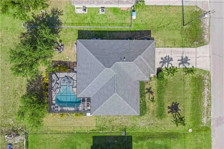 An aerial view reveals a stunning home with lush landscaping, a sparkling pool, separate spa, and spacious outdoor patio, offering a perfect blend of luxury and privacy.