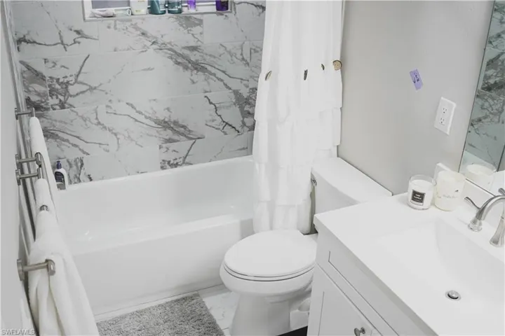 Full bathroom featuring shower / tub combo with curtain, vanity, and toilet