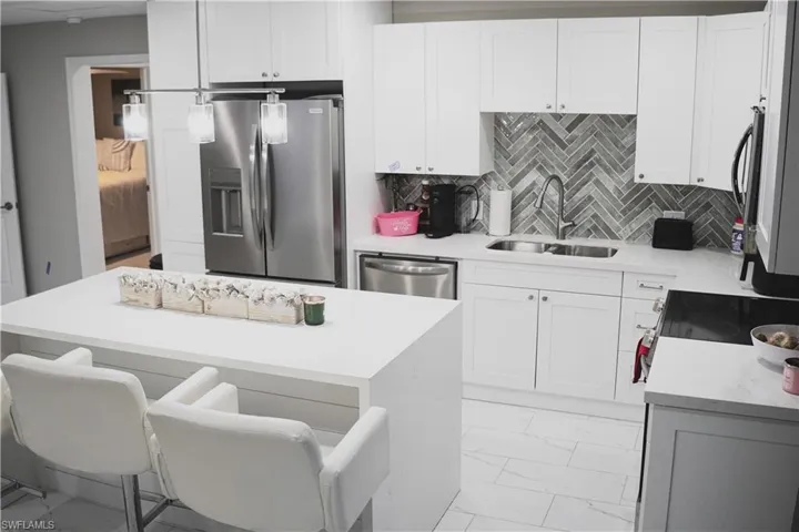Kitchen featuring stainless steel appliances, tasteful backsplash, sink, and white cabinets