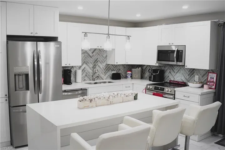 Kitchen featuring sink, a center island, appliances with stainless steel finishes, a kitchen breakfast bar, and pendant lighting