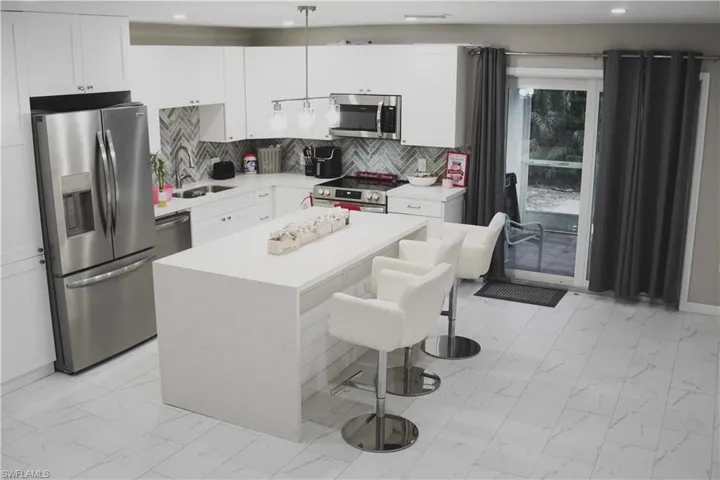 Kitchen featuring sink, a breakfast bar area, hanging light fixtures, a center island, and stainless steel appliances