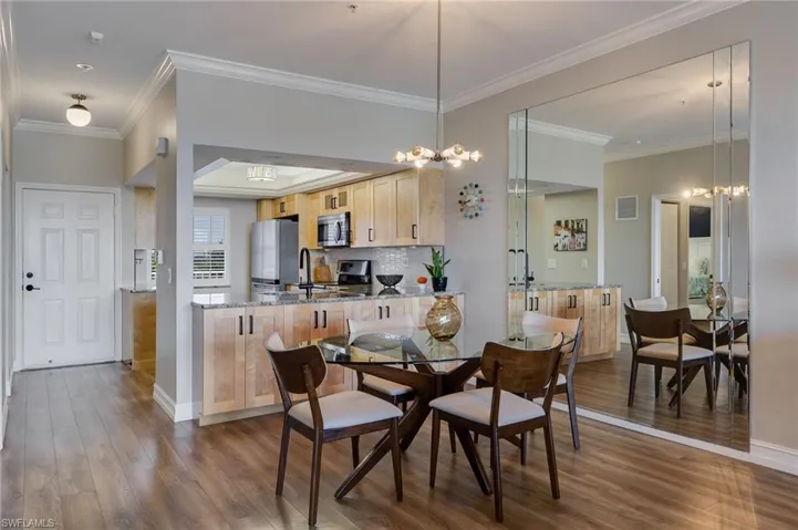 Dining room featuring ornamental molding, dark wood-style flooring, a chandelier, and a raised ceiling
