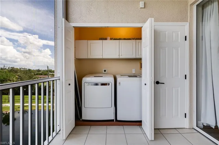 Washroom with light tile patterned floors, cabinet space, and washing machine and dryer